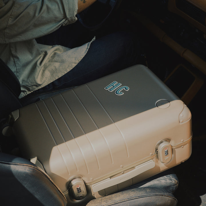 Two suitcases with 'HC' branding on a vehicle seat