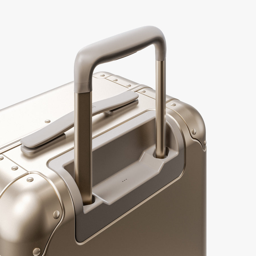 Champagne Gold | Extended luggage handle view of Aluminum Carry-On Plus in Champagne Gold