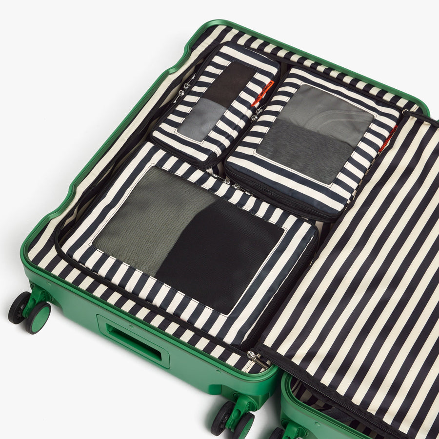 Set of Four / Poplin Stripe Black | Poplin Stripe Black compressible packing cubes neatly organized inside a Jungle Green suitcase