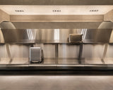 Display wall inside the Monos Georgetown store featuring aluminum luggage showcased against brushed steel shelving and soft ambient lighting.