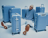 The Monos Hybrid Luggage Collection in Elemental Blue, featuring a range of sizes from carry-on to check-in. Captured in a modern studio setting, highlighting the sleek aluminum-corner design and smooth matte finish that define the Hybrid series.